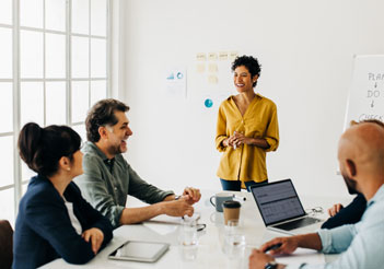 A woman in a yellow shirt leading a meeting